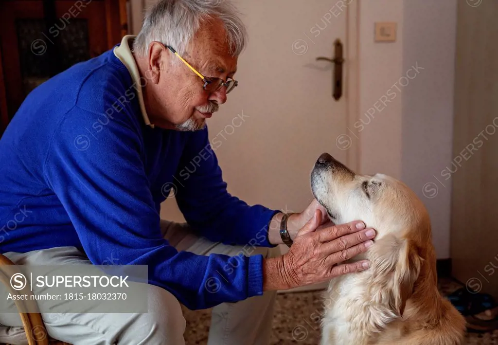 Senior man with dog sitting at home