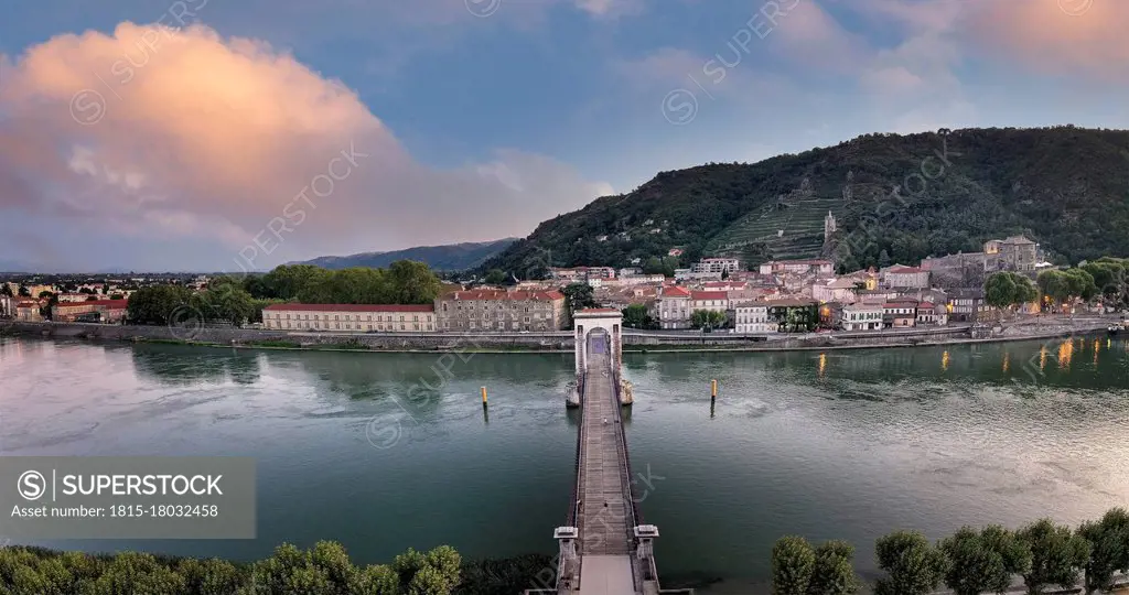 France, Ardeche, Tournon-sur-Rhone, Panorama of Passerelle Marc Seguin bridge and riverside town at dusk