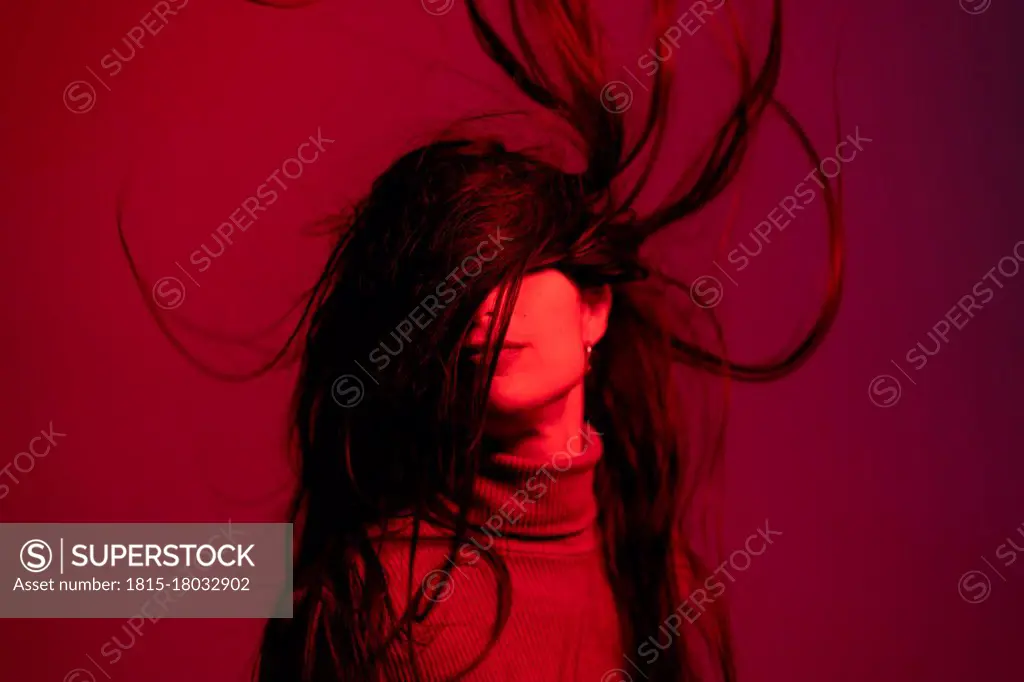 Woman tossing hair against red background