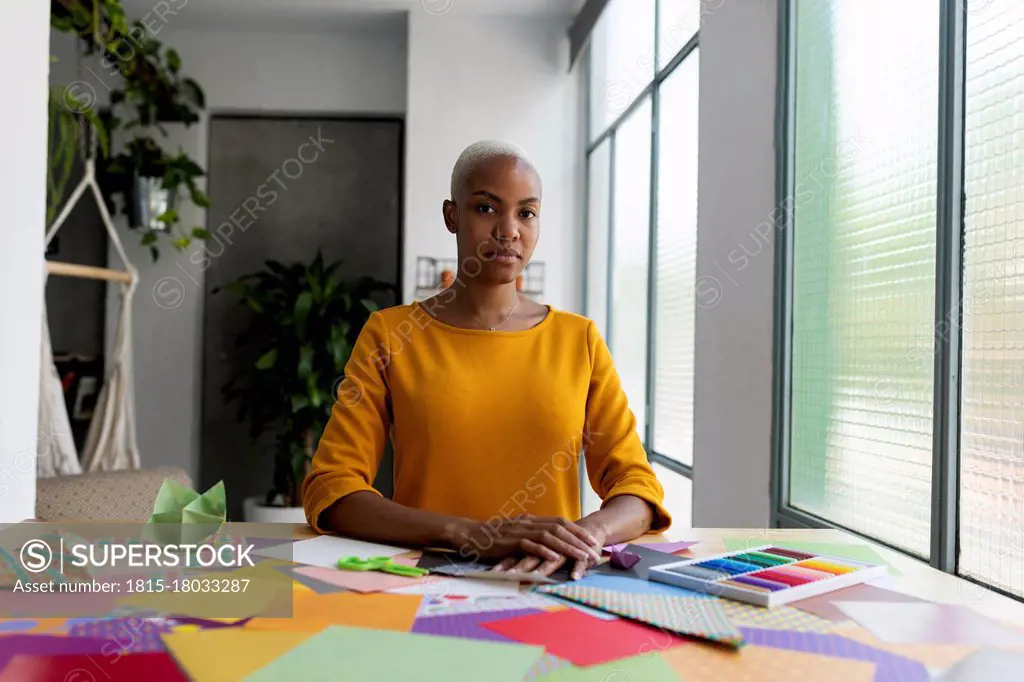 Origami artist sitting in studio with colorful papers