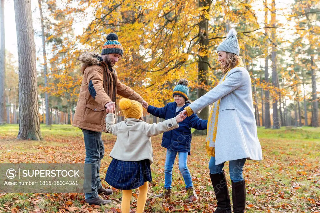 Children holding parents hand while playing in forest