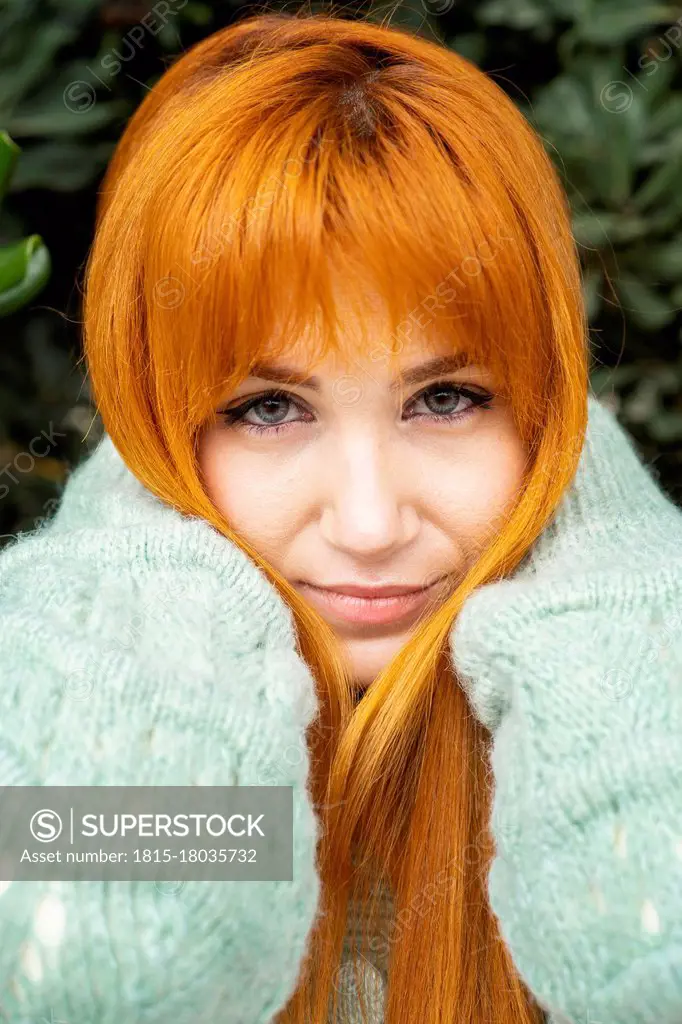 Beautiful woman with hand in hair against tree