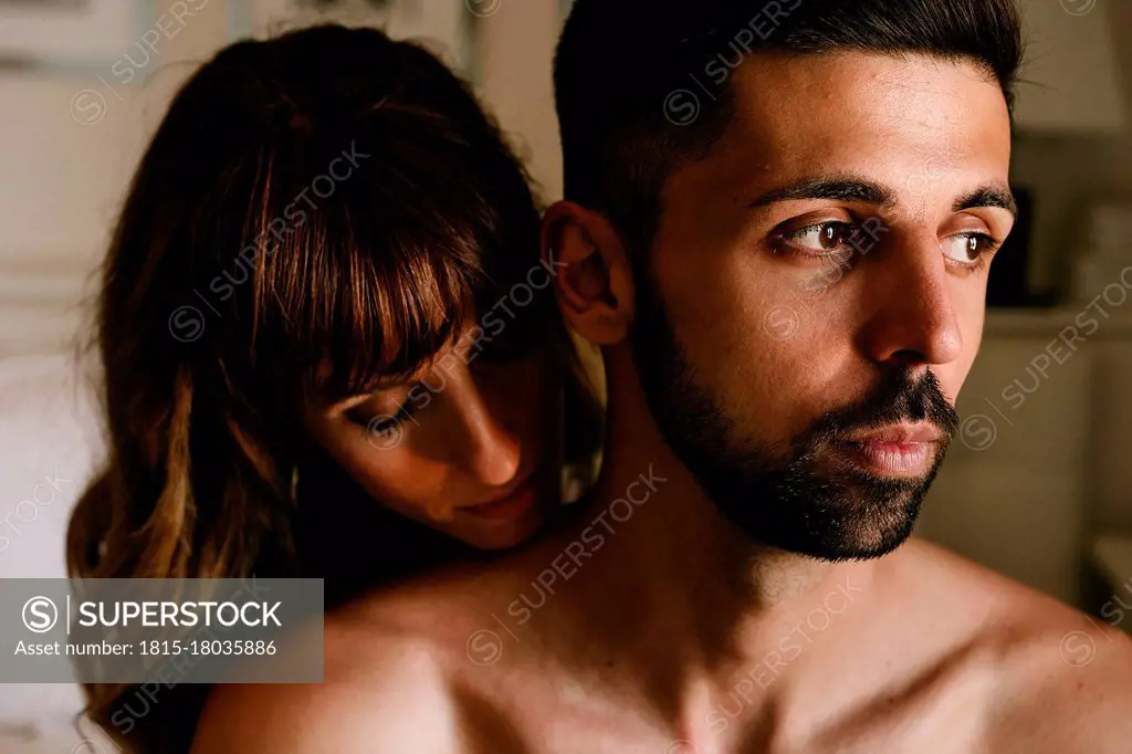 Affectionate woman behind thoughtful man at home