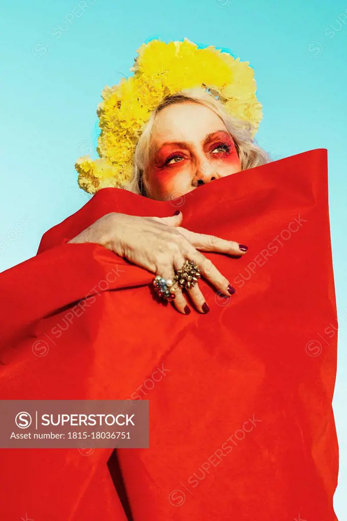 Beautiful senior woman wrapped in red fabric on sunny day