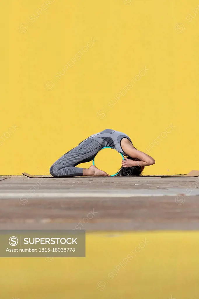 Woman doing yoga wheel exercise while bending over backwards by wall