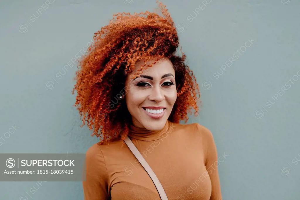 Smiling beautiful woman against gray wall