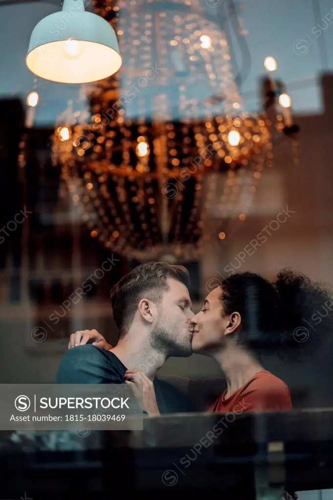 Boyfriend and girlfriend kissing each other while sitting at cafe