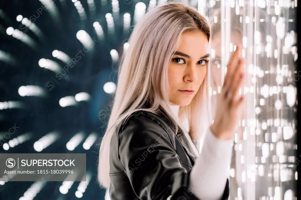 Attractive woman leaning on illuminated glass wall