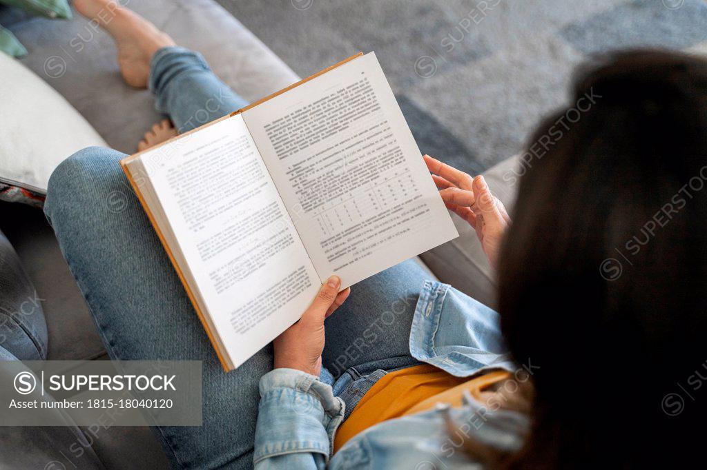 Profile photo of attractive aged mature homey lady sitting comfy sofa couch  barefoot reading interesting historic novel book stay home quarantine time  weekend living room indoors Stock Photo