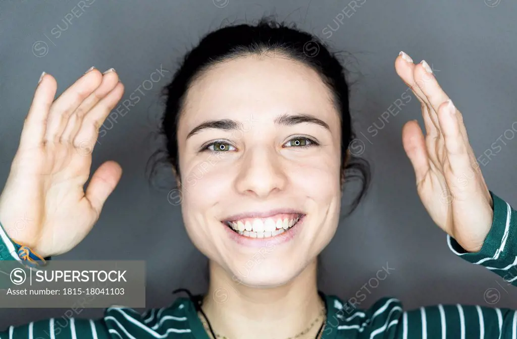 Cheerful woman gesturing against gray background