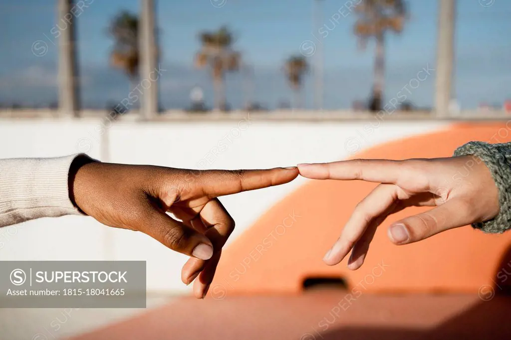 Close-up of friends index finger pointing each other outdoors