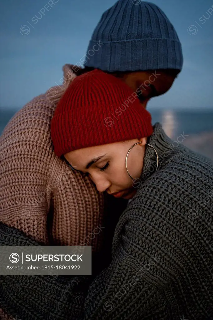 Young woman embracing friend while standing outdoors