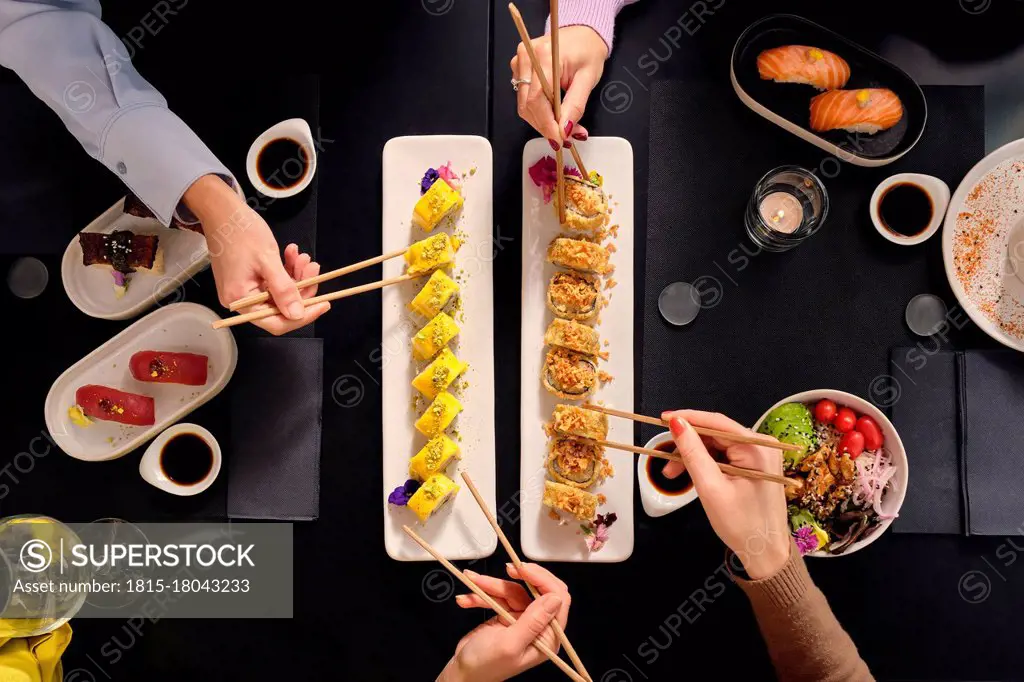 Female customers eating fresh sushi with chopsticks at restaurant