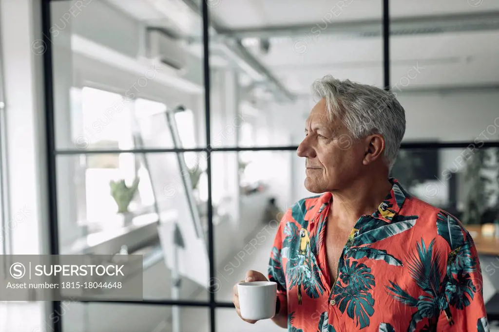 Businessman holding coffee cup while standing at office