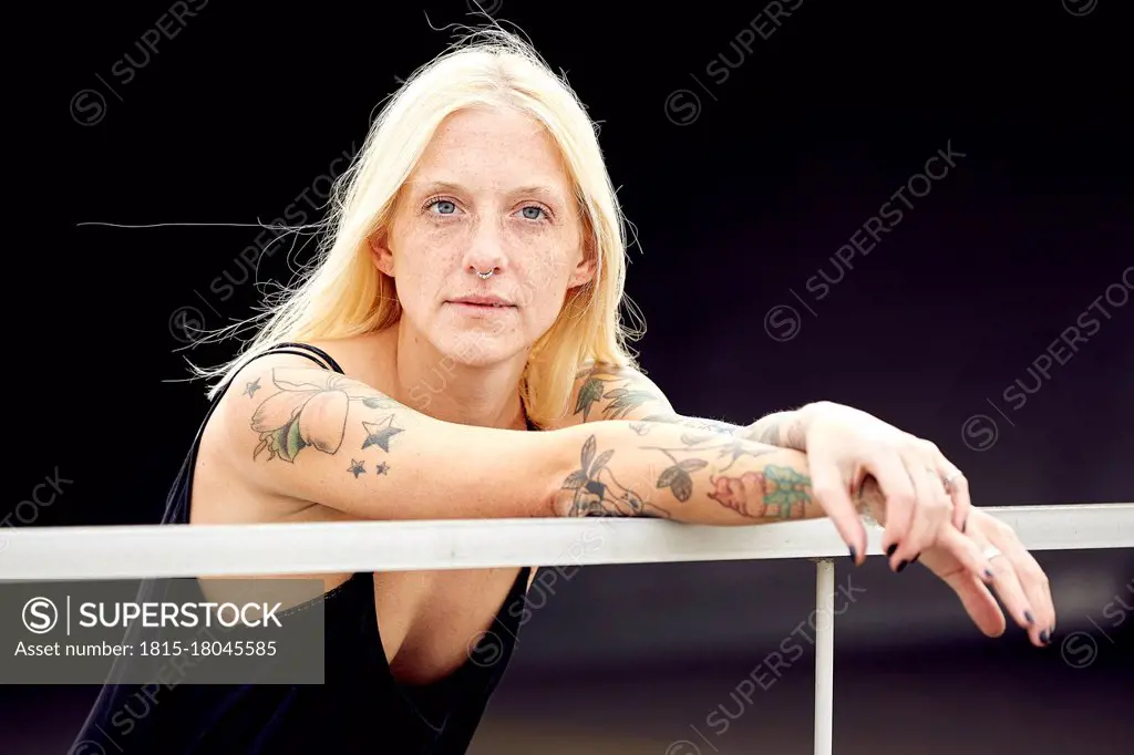 Young woman with blond hair looking away while leaning on railing