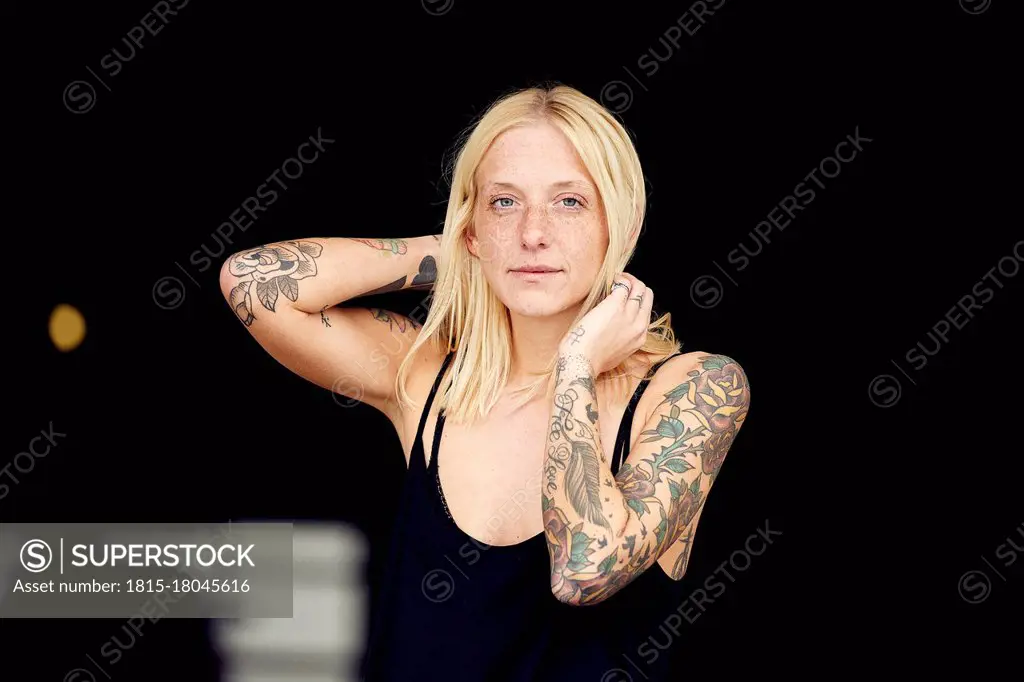 Tattooed woman with hand in hair standing at parking garage