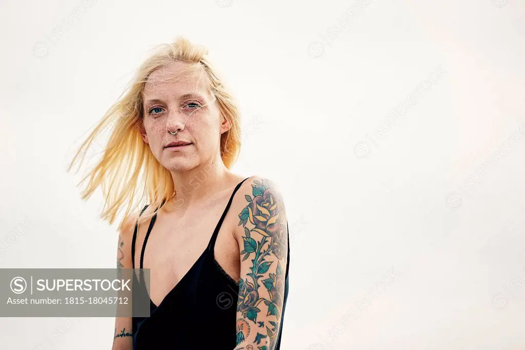 Tattooed young woman against clear sky