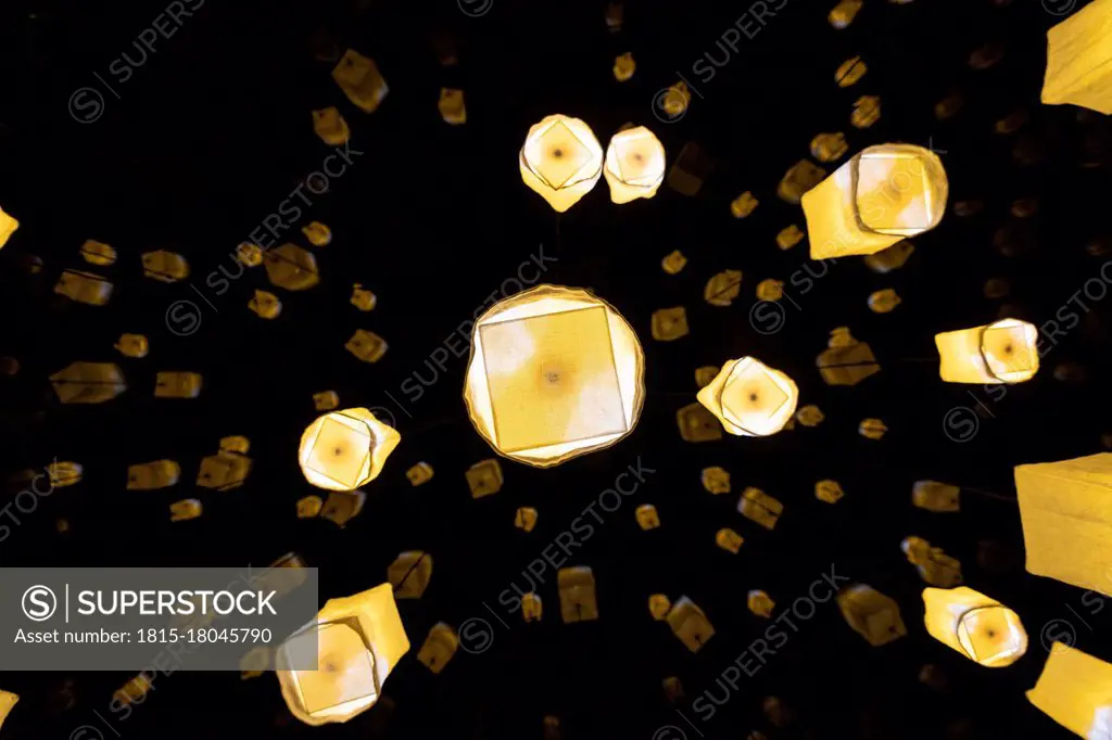 Illuminated design lamps hanging outdoors at night