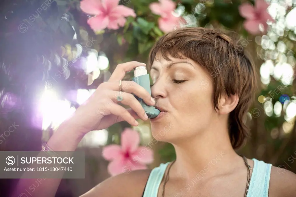 Young woman breathing through asthma inhaler