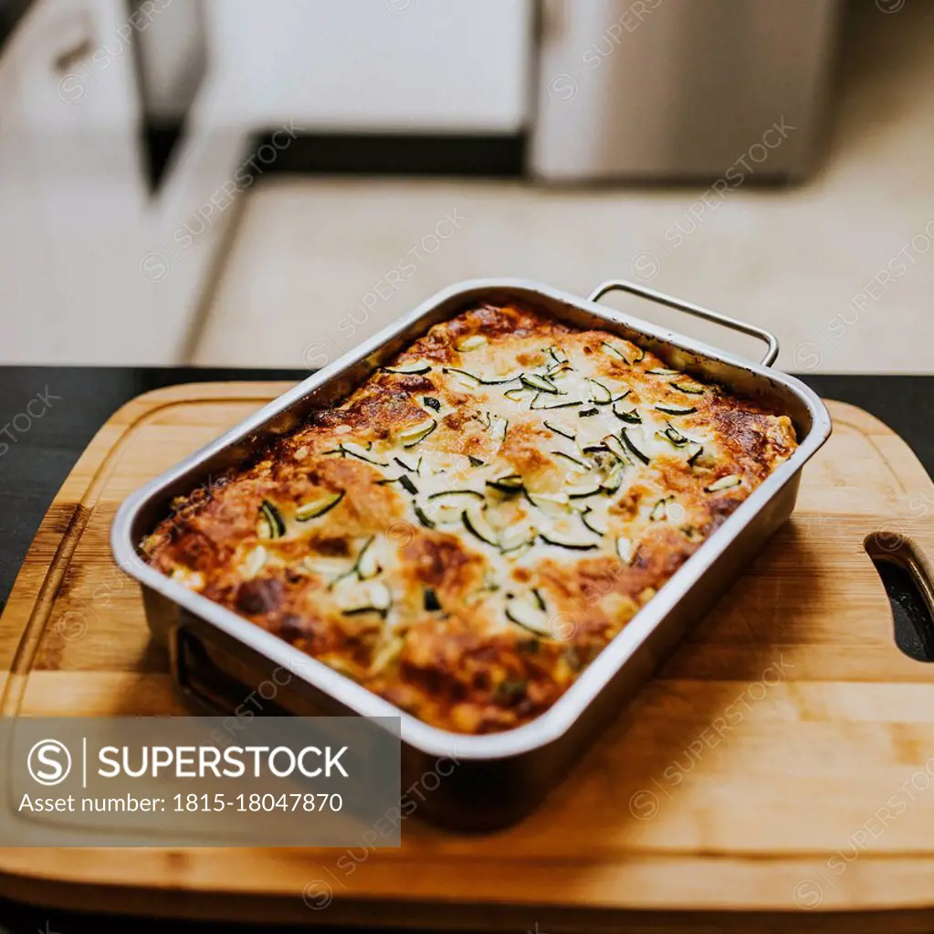 Homemade cooked lasagna with zucchini in tray on cutting board at home