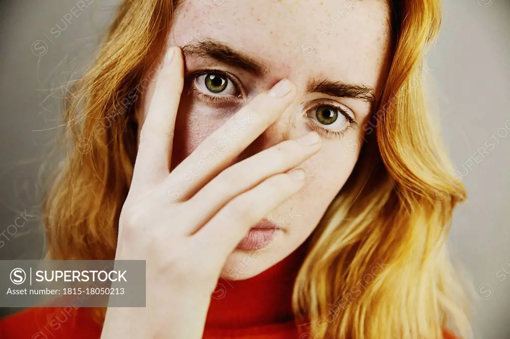 Blond teenage girl covering face with hand