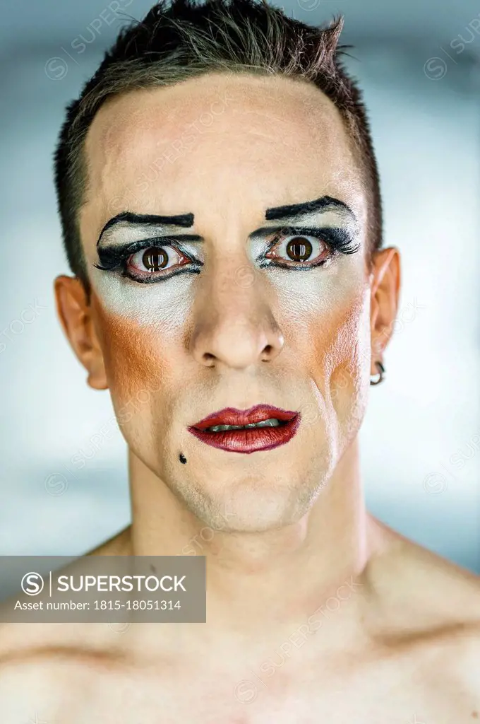 Close-up portrait of drag queen with make-up against gray background