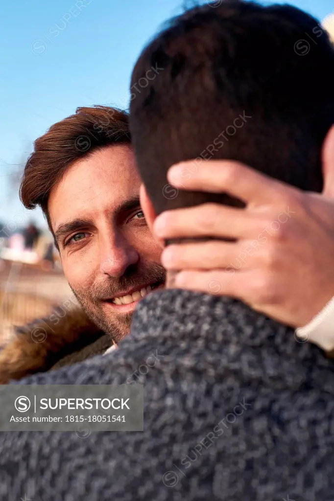 Close-up of smiling man embracing boyfriend