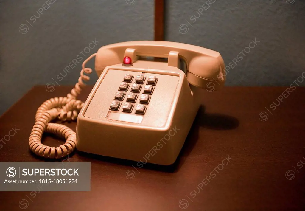 Peach color telephone on wooden table