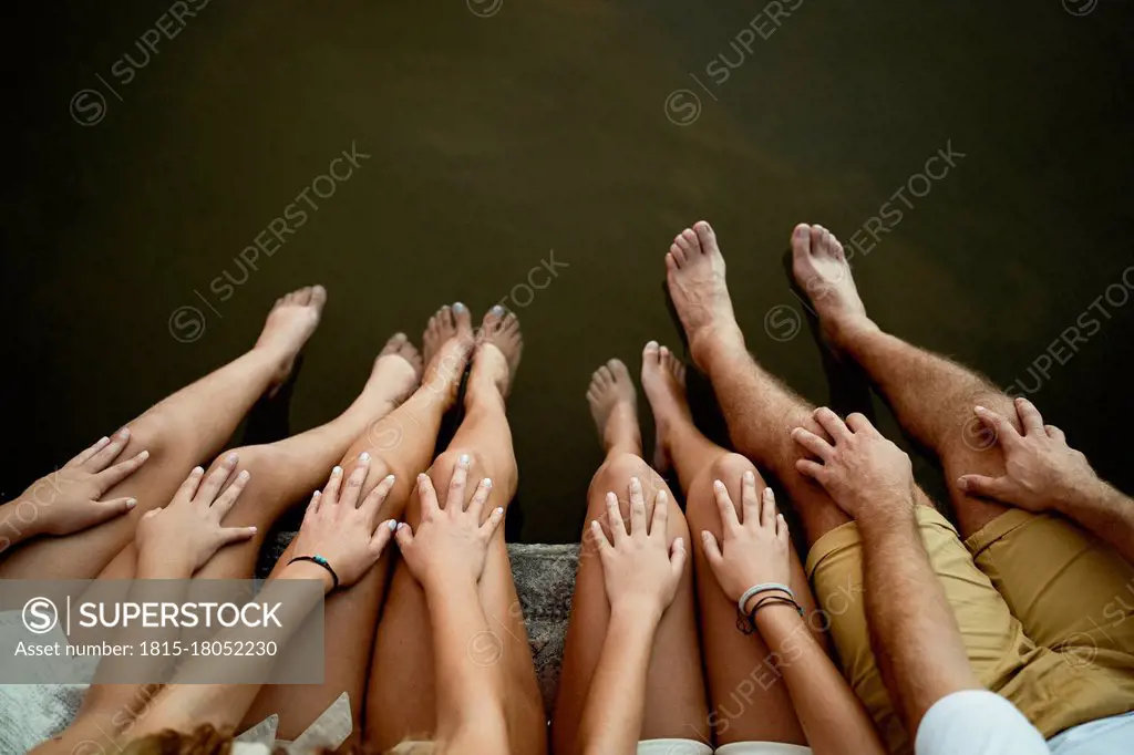 Family dangling legs over lake