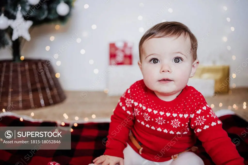 Cute baby girl staring while sitting at home during Christmas