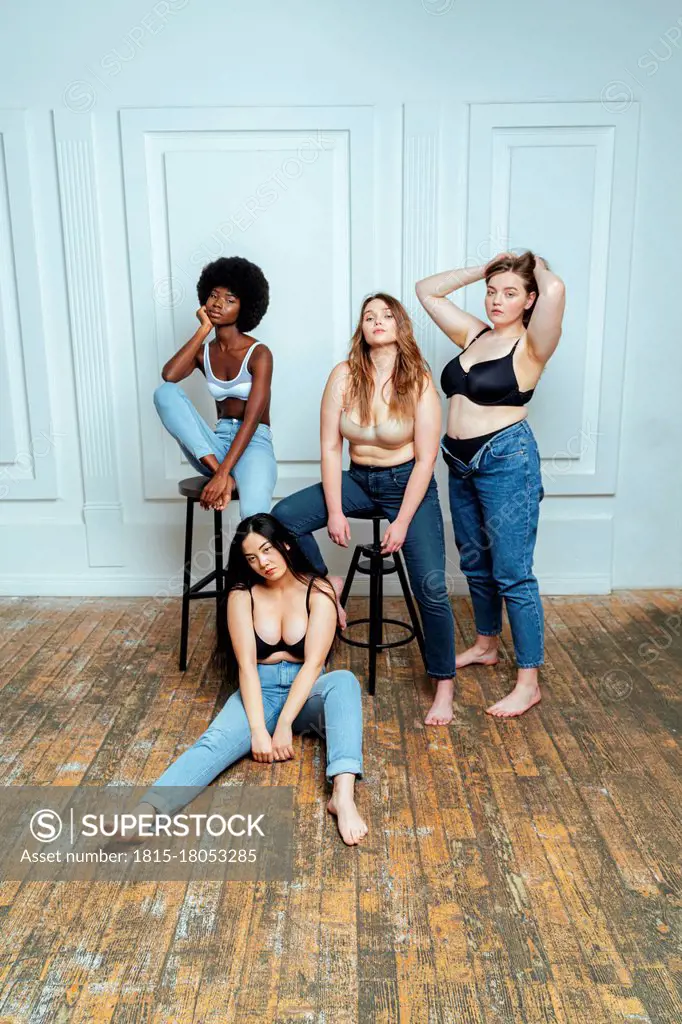 Multi-ethnic group of women wearing bras and jeans posing against