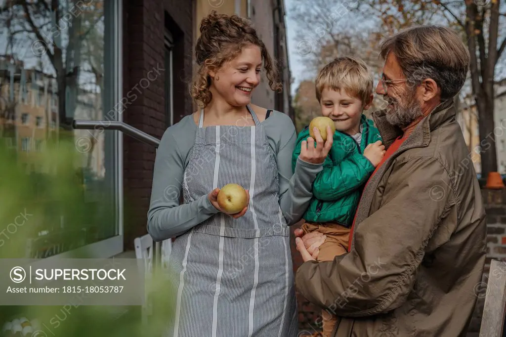 Smiling saleswoman selling apple to father and son at retail store