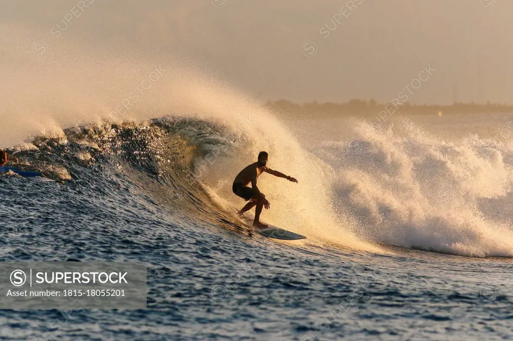 Mid adult man surfing on sea during sunset