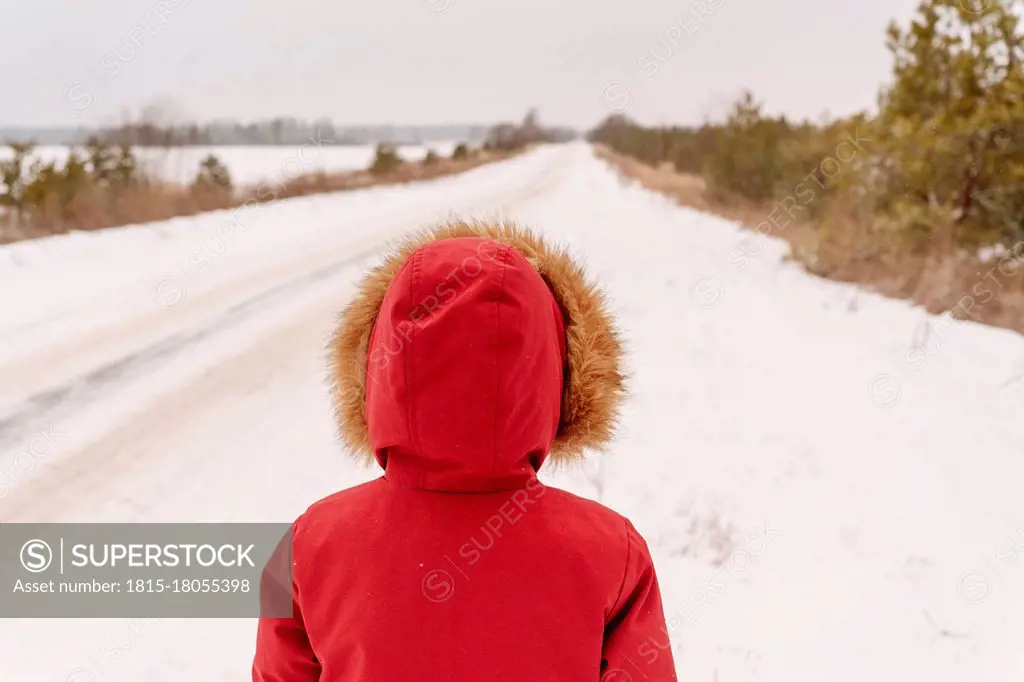 Boy wearing red winter coat standing on snowy landscape