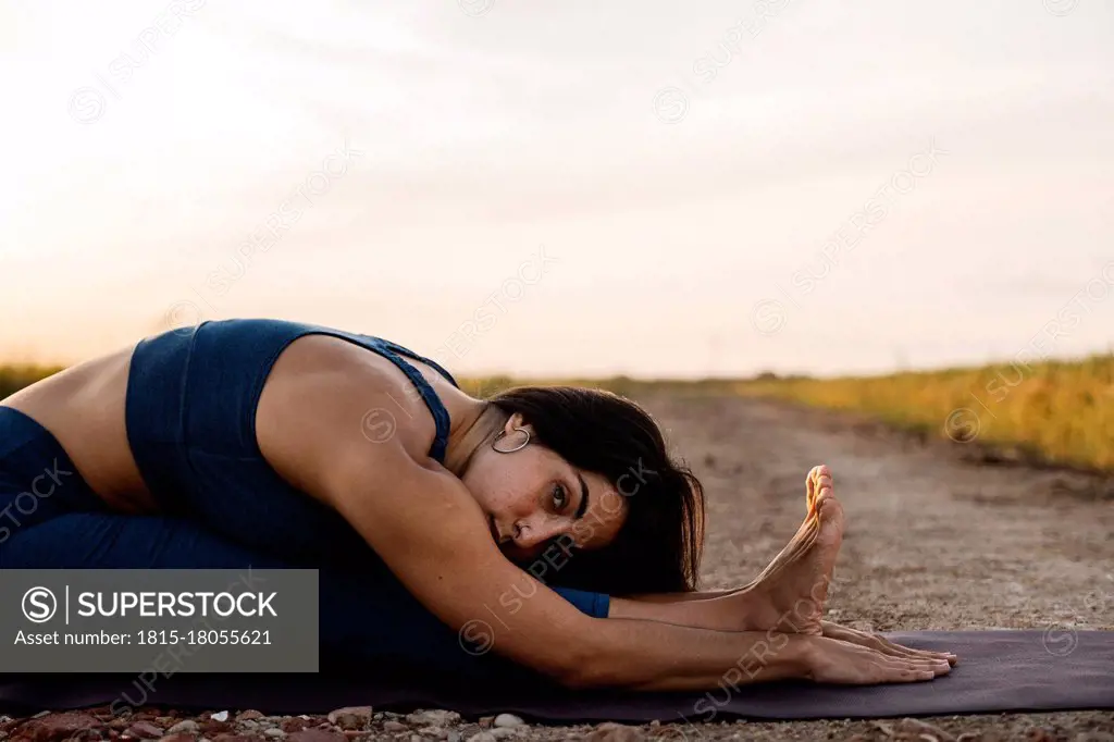 Woman practicing Paschimottasana on road