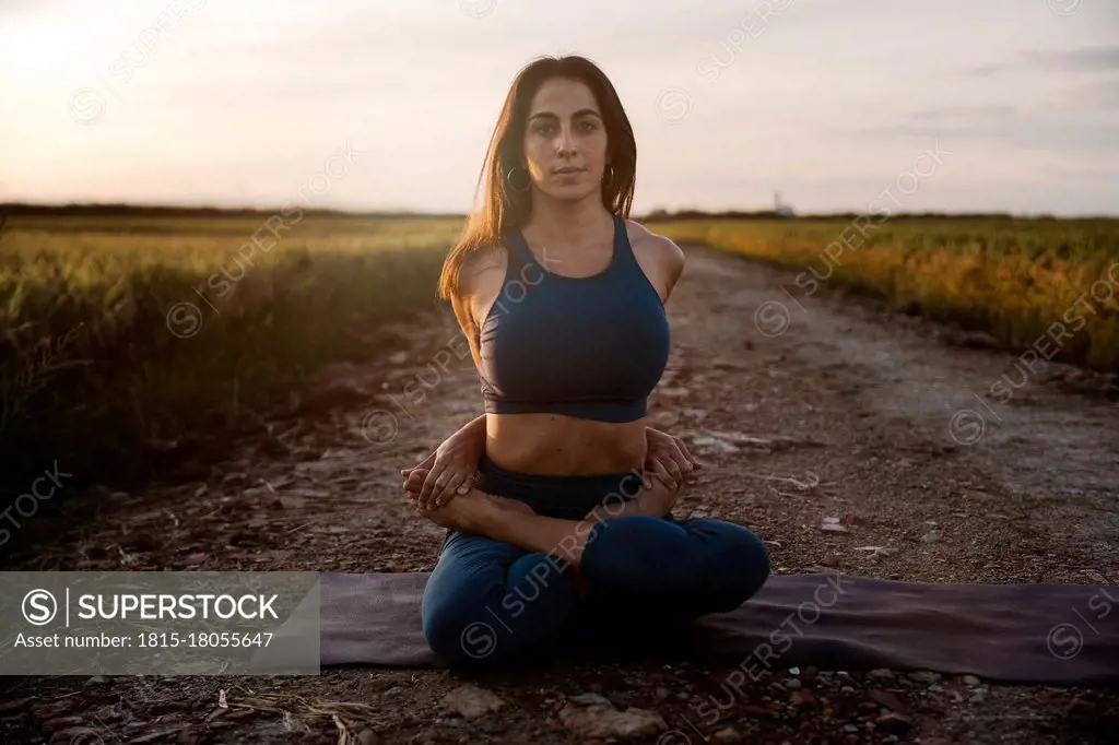 Woman sitting cross-legged practicing yoga against sky