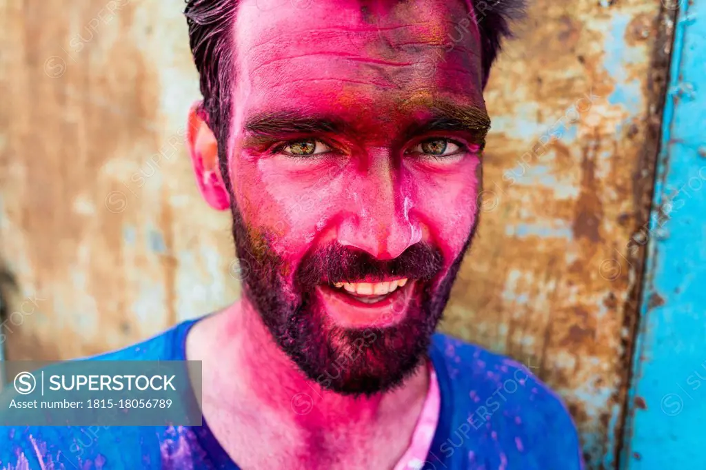 Close-up of smiling bearded man with pink face during Holi festival