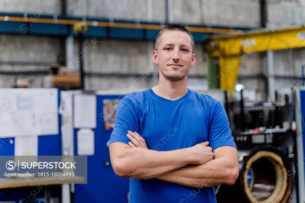 Confident male manual worker with arms crossed standing at industry