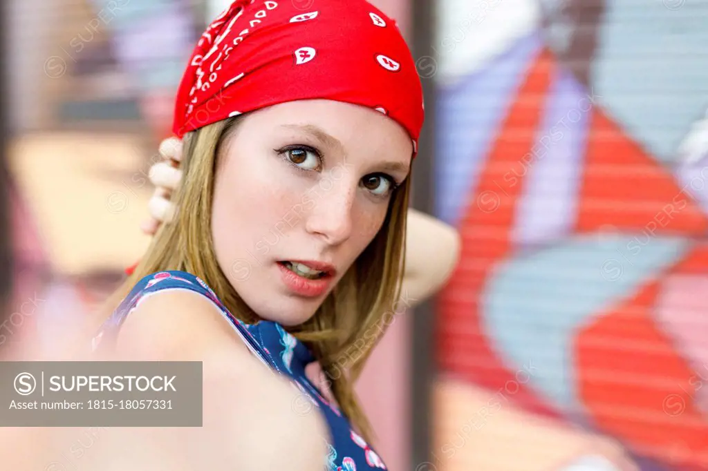 Beautiful young woman wearing bandana while standing by colorful shutter