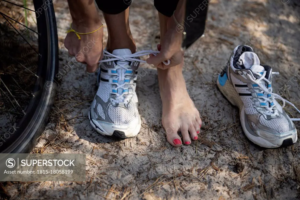 Female athlete tying sports shoelace by tire