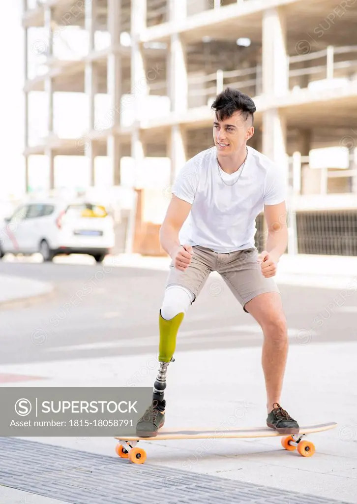 Smiling amputated man skateboarding on street