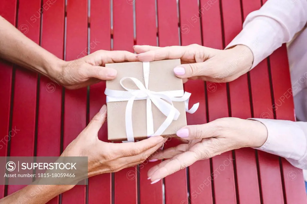 Woman giving gift to female friend at table in restaurant