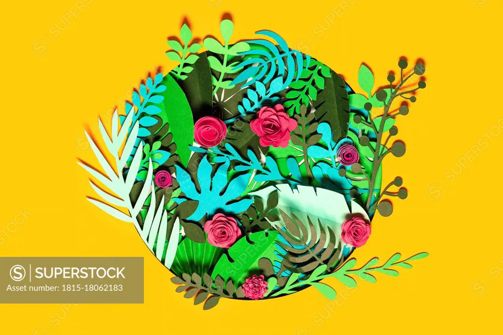 Green paper plants with flowers over yellow background