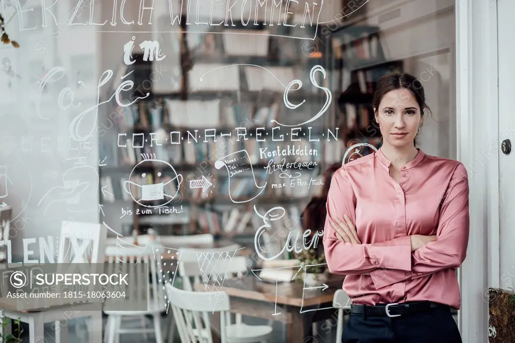 Confident female entrepreneur with arms crossed outside coffee shop