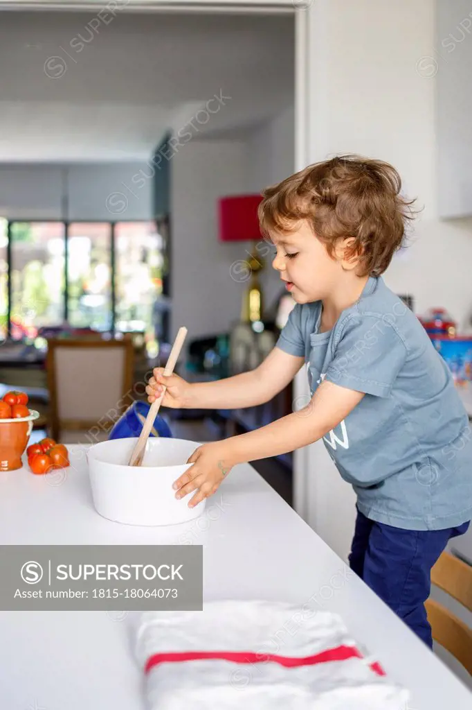 Cute boy cooking in kitchen at home