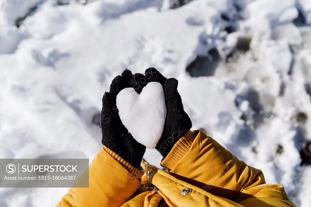 Girl's hands holding heart shaped snow in park