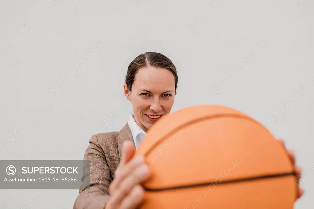 Smiling female professional with basketball during break