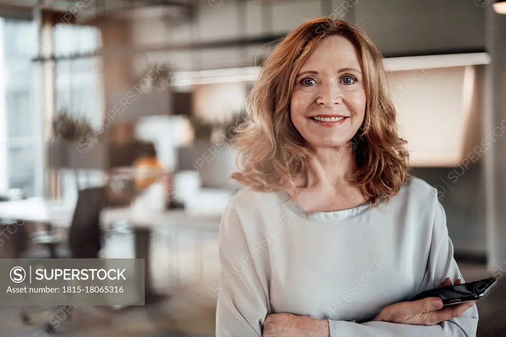 Elegant female entrepreneur with arms crossed in office