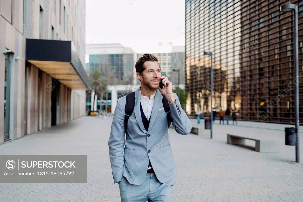 Businessman standing with hand in pocket talking on smart phone