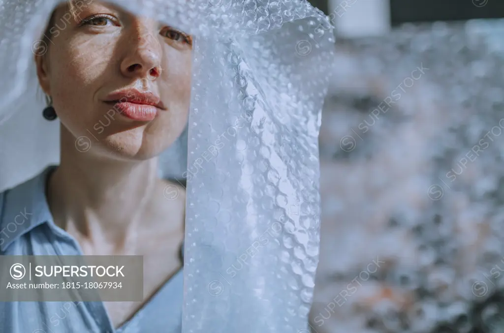 Female artist covered in bubble wrap at art studio